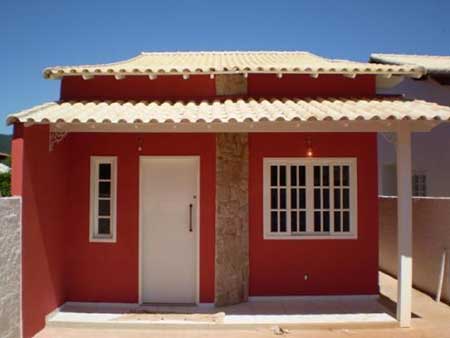 Uma pequena casa vermelha charmosa e com telhado branco