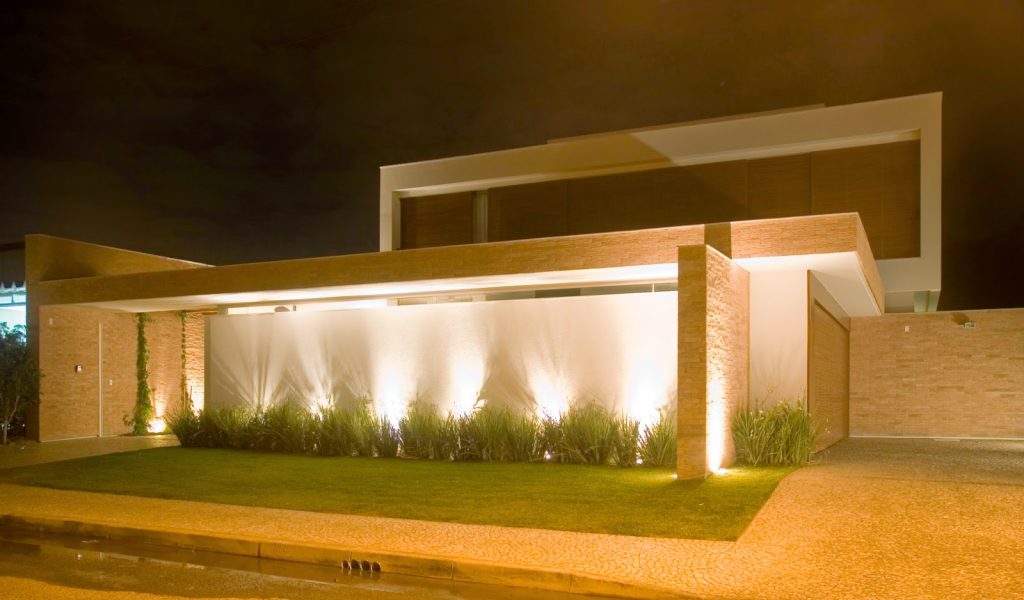 Jardim com muro na frente de casa com luzes para cima