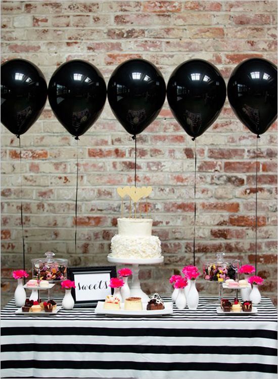 Balões pretos flutuantes com mesa listrada em preto e branco