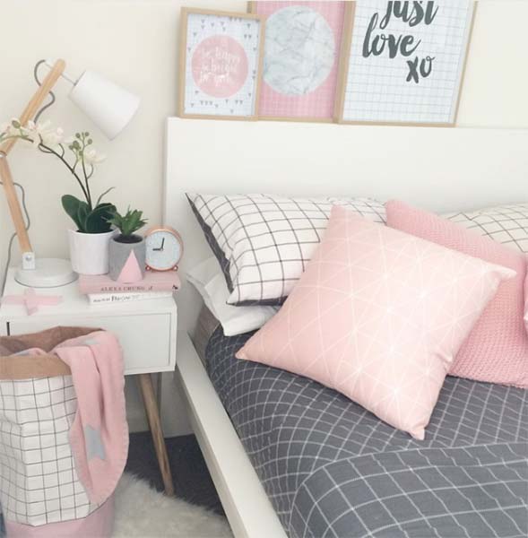Cama com lençol cinza e almofadas rosas