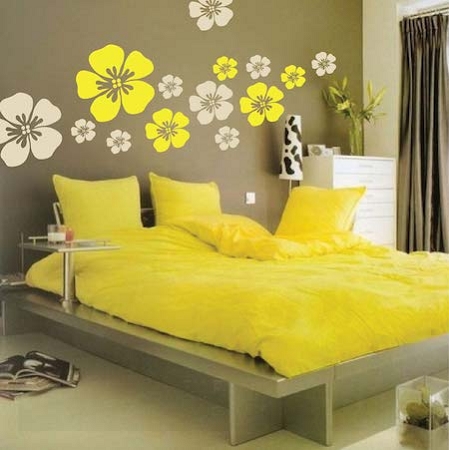 Cama no quarto amarelo com floers amarelas na parede