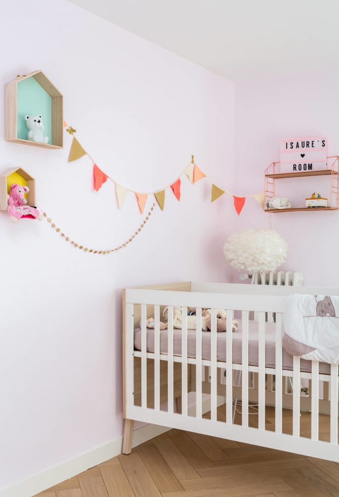 Parede branca colocada em um quarto de bebe com bandeirinhas