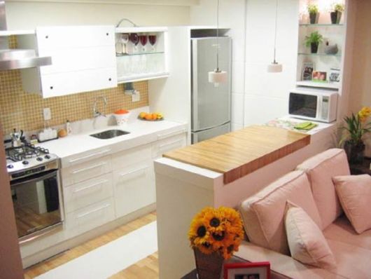 sofá rosa na sala pequena em conjunto com cozinha americana