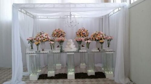 pergolado sendo usado como cobertura de mesa de festa de casamento com decoração com cortinas brancas